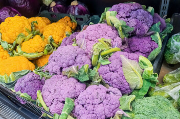 Bunches of fresh yellow, purple and green cauliflower heads at the farmers market