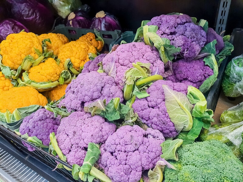 Bunches of fresh yellow, purple and green cauliflower heads at the farmers market