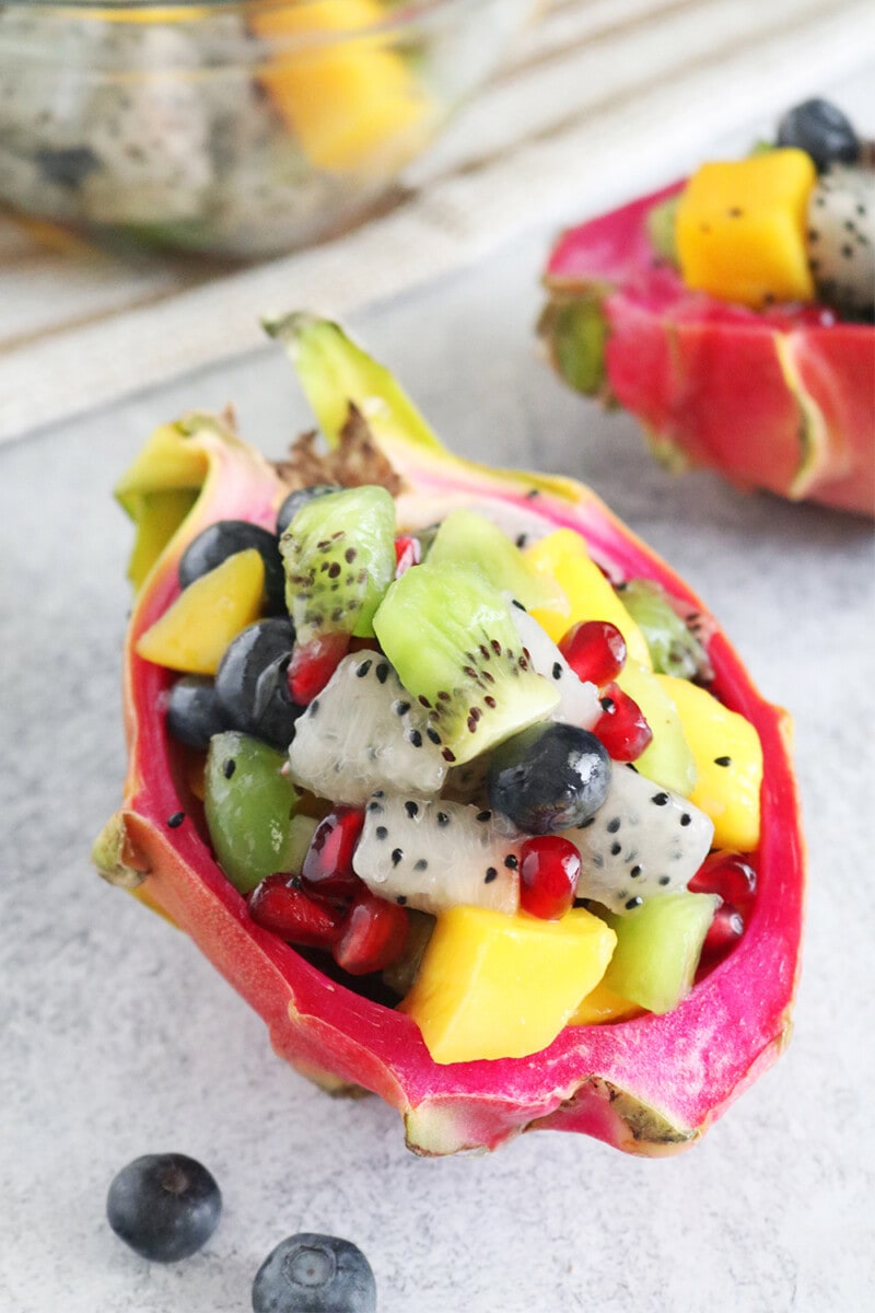 Dragon fruit salad with cubed dragon fruit, kiwi, mango, blueberries, and pomegranate in a hollowed out dragon fruit peel.