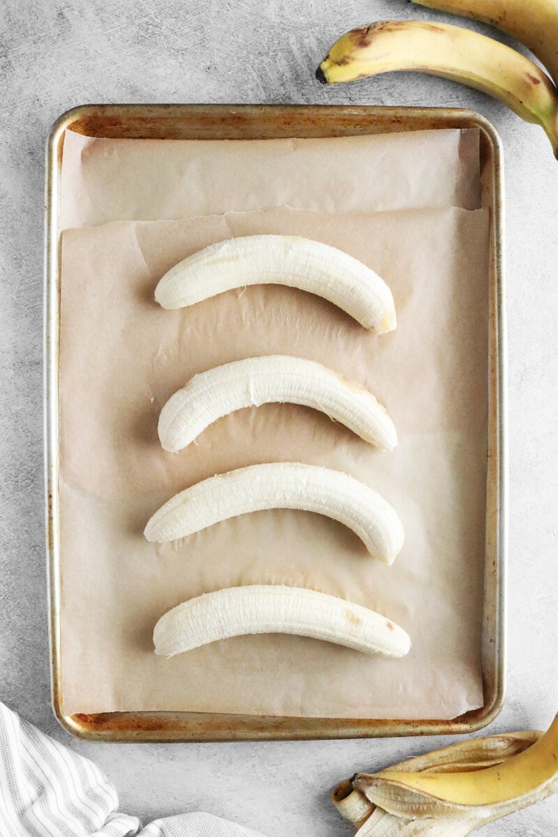 whole peeled bananas on a baking sheet with parchment paper