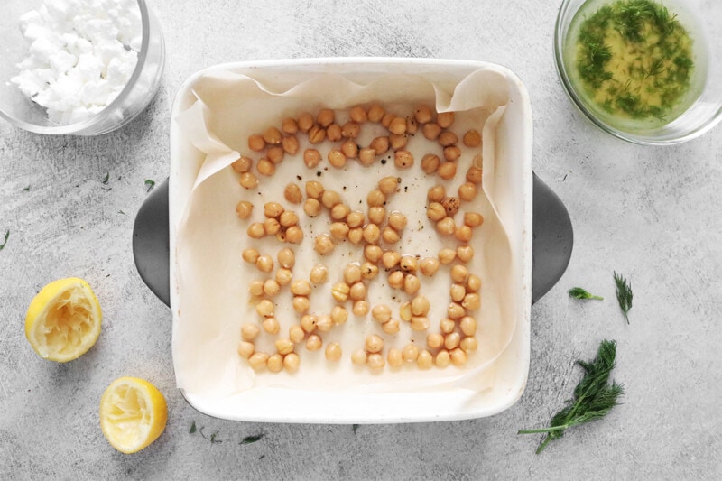 Chickpeas on parchment paper in a baking dish.