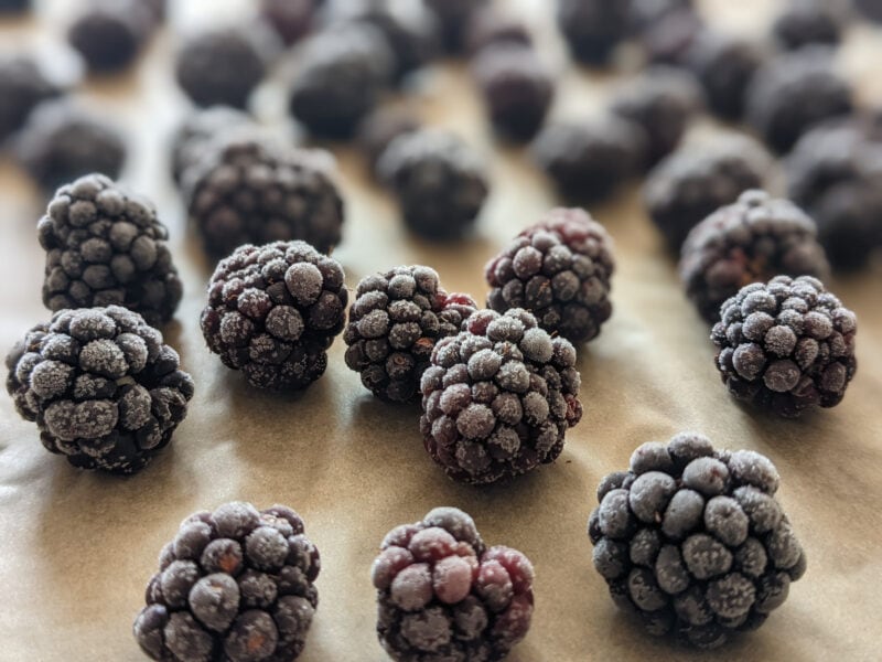 Close-up view of frozen strawberries on a parchment-lined cookie sheet