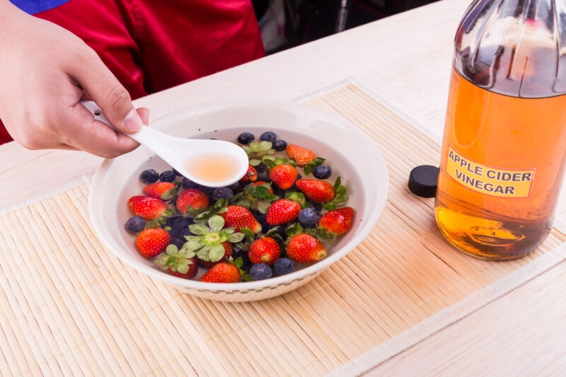 Cleaning berries in an apple cider vinegar fruit wash to neutralize pesticides.