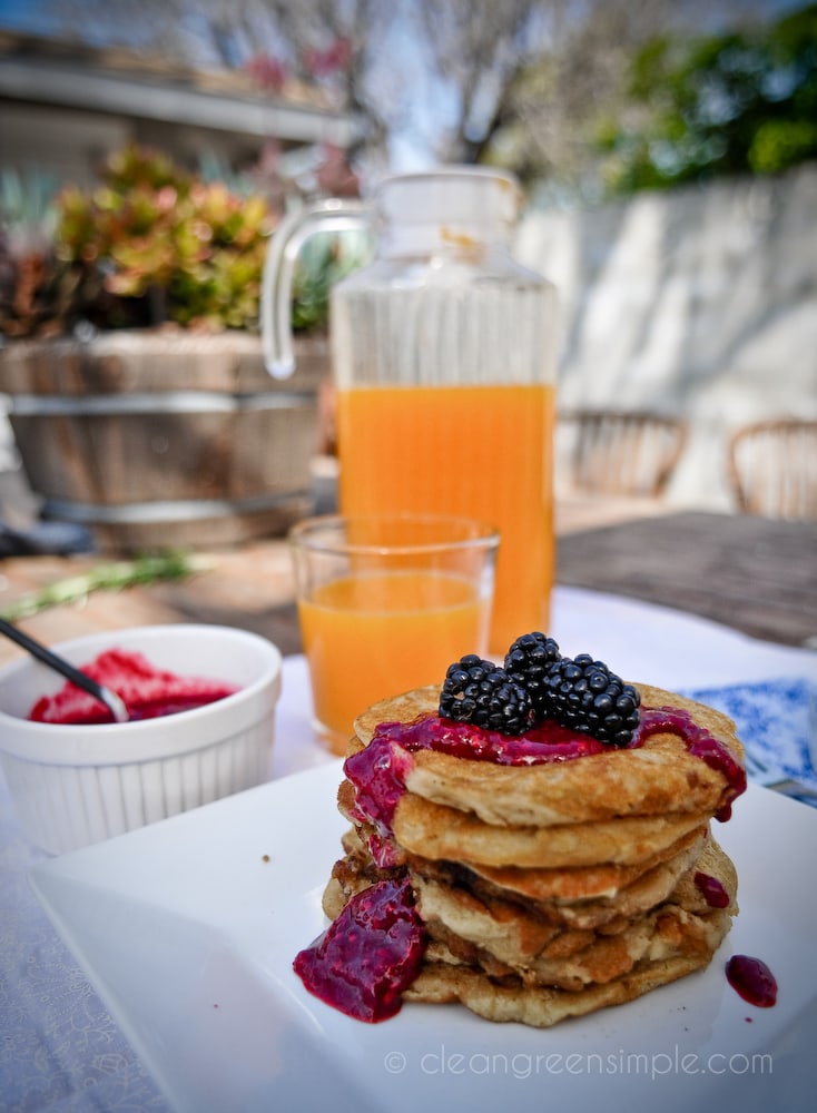Gluten-free vegan pancakes with blackberries on a while plate with juice.