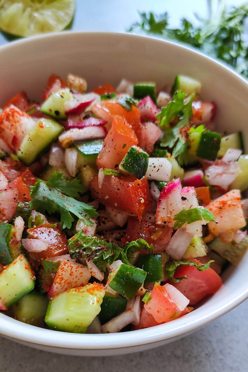 Vegan kachumber salad with chopped tomato and radishes in a bowl.