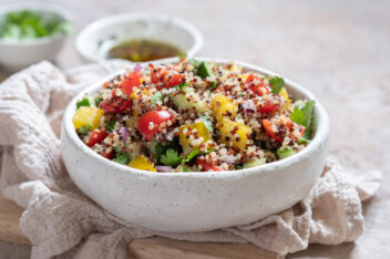 A bowl of vegan quinoa salad with chopped cherry tomatoes and peppers.