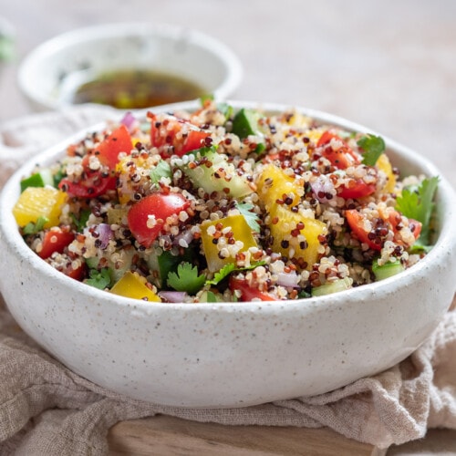 A bowl of vegan quinoa salad with chopped cherry tomatoes and peppers.