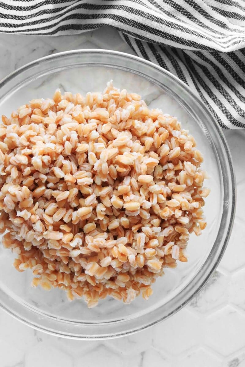 Cooked farro in a glass bowl on a white background