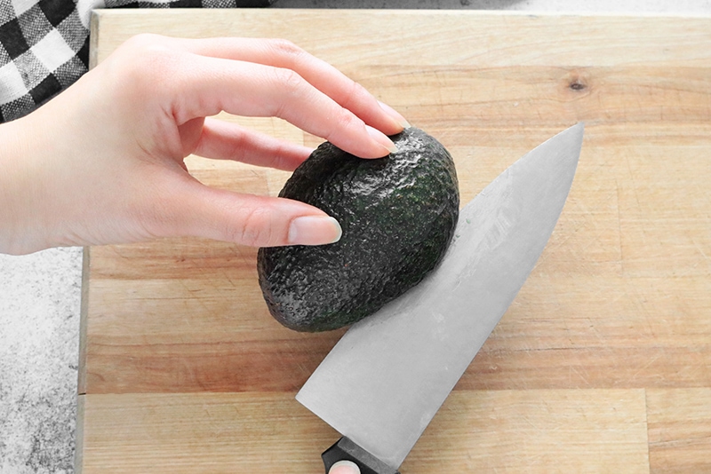 Cutting an avocado with a chef's knife on a cutting board