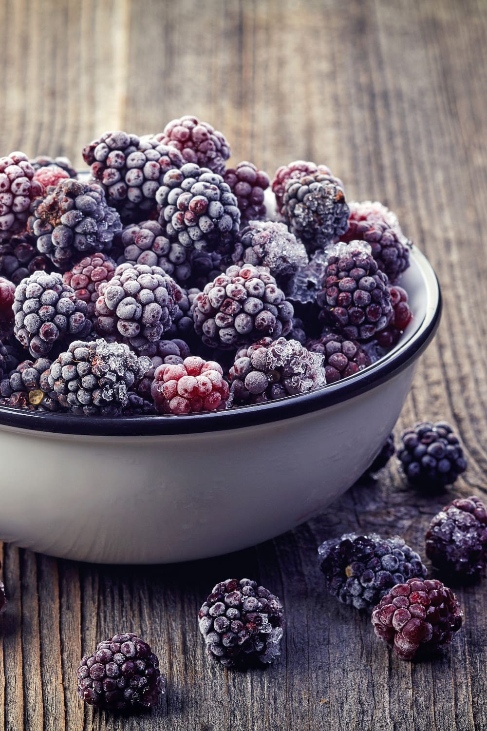 Close-up view of frozen blackberries in a bowl on a wooden table