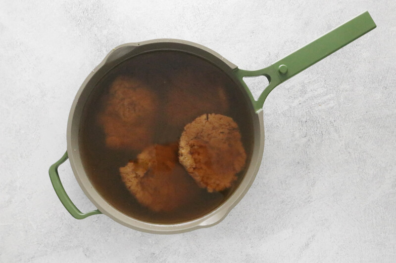 cooking seitan in a large pot with broth and soy sauce