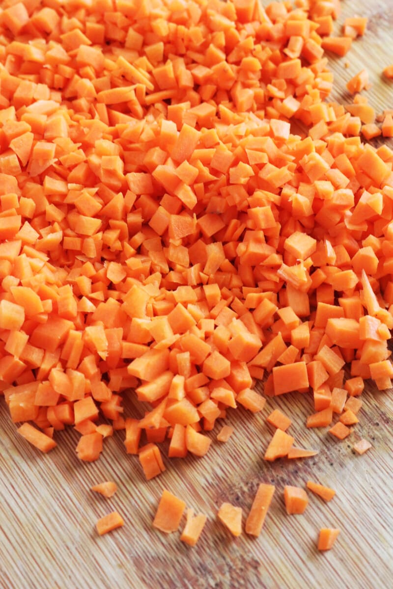Minced carrots on a wooden cutting board.
