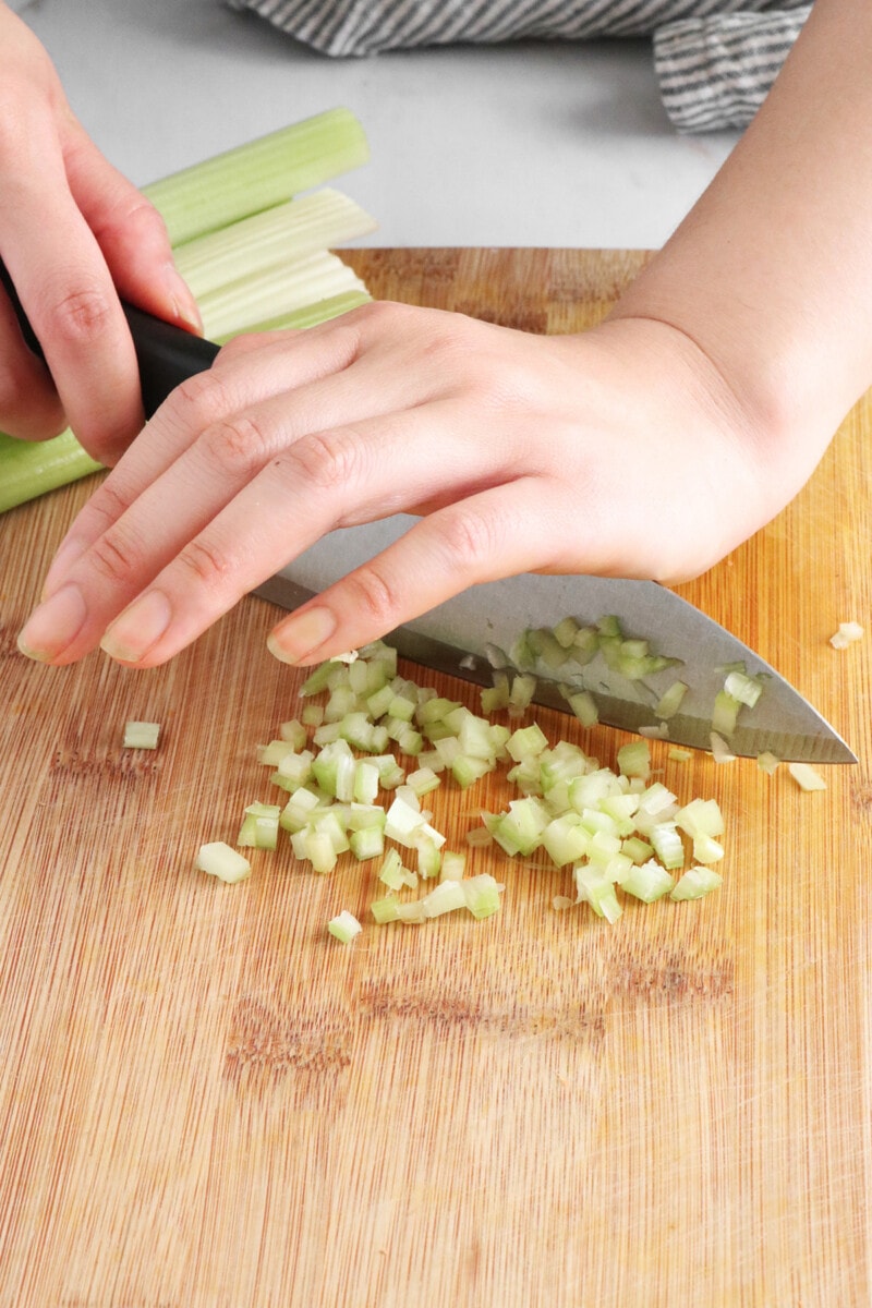 Mincing celery on a wooden cutting board.