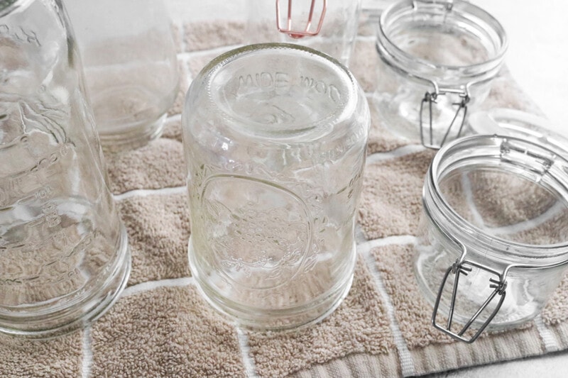 Glass, wide-mouth jars drying on a towel.