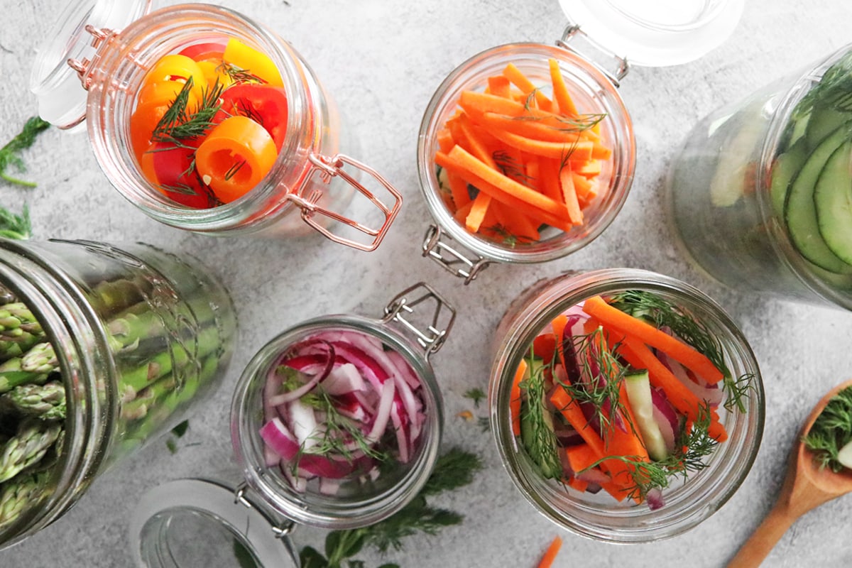 Vegetables and fresh herbs in jars.
