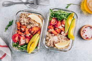 Affordable vegan meal prep containers filled with quinoa, tomatoes, avocado, and greens.