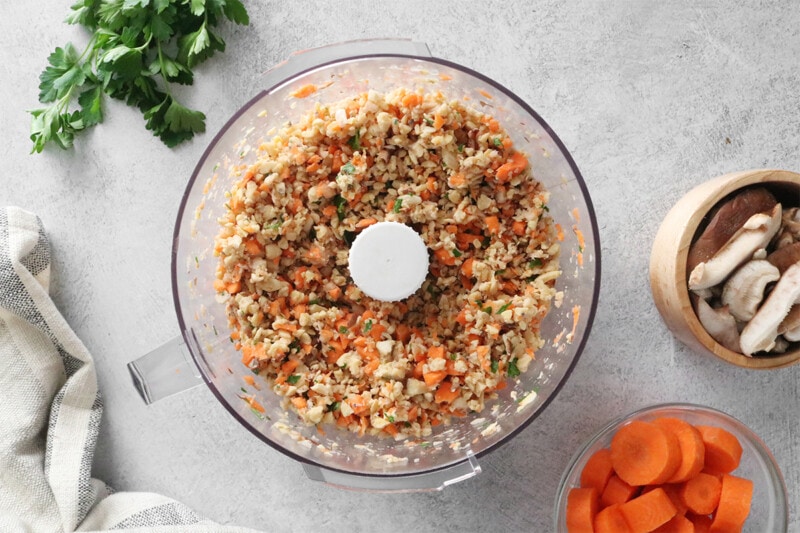 Tempeh, carrots, and mushrooms in a food processor.