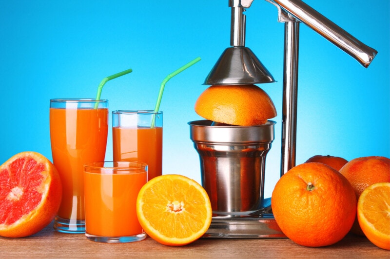 Manual lever Juicer with oranges and grapefruit on blue background