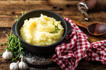 Mashed potatoes in a cast iron crock on a wooden table