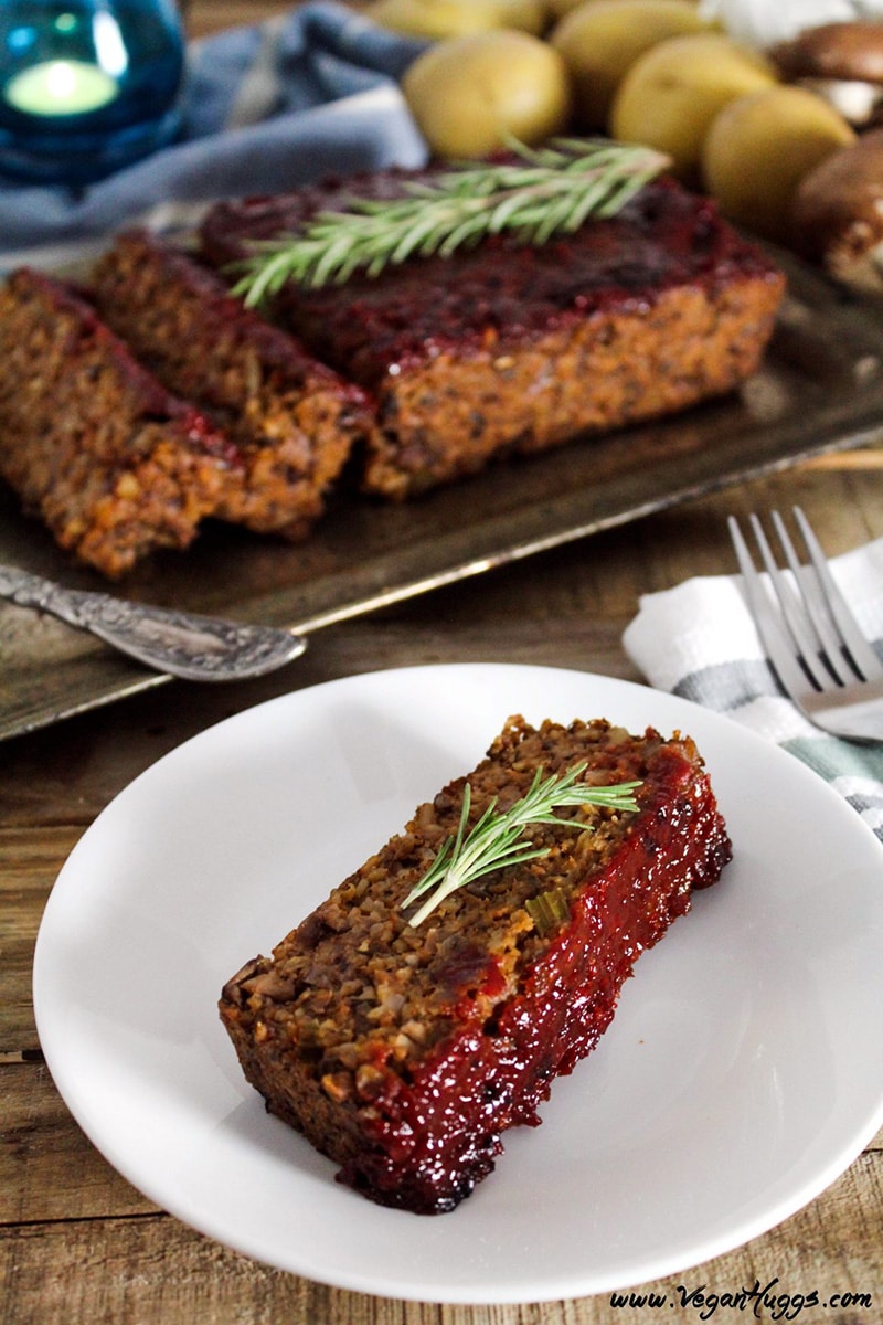 A slice of meatless mushroom loaf on a plate, topped with a sprig of fresh rosemary.