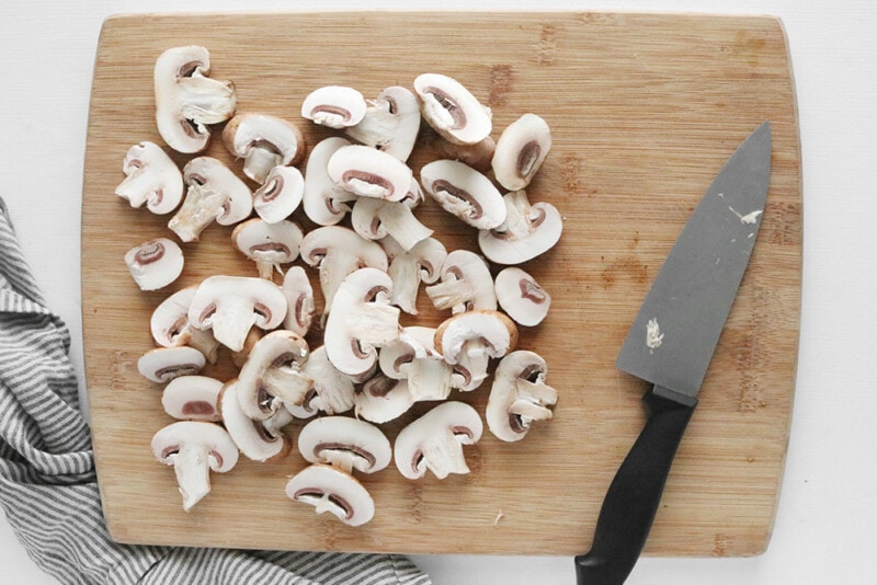 sliced mushrooms on a bamboo cutting board with a knife