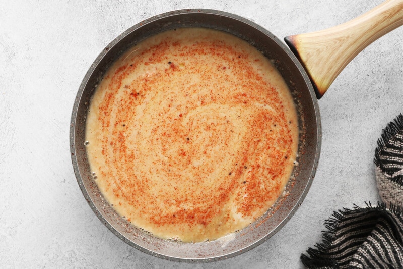 adding seasonings to roux in a skillet