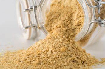 Nutritional yeast spilling out of a glass storage jar.
