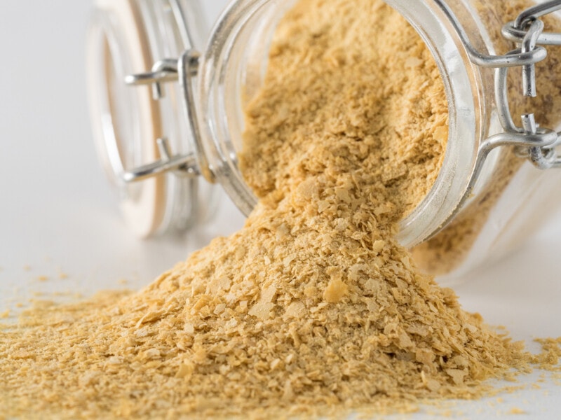 Nutritional yeast spilling out of a glass storage jar.