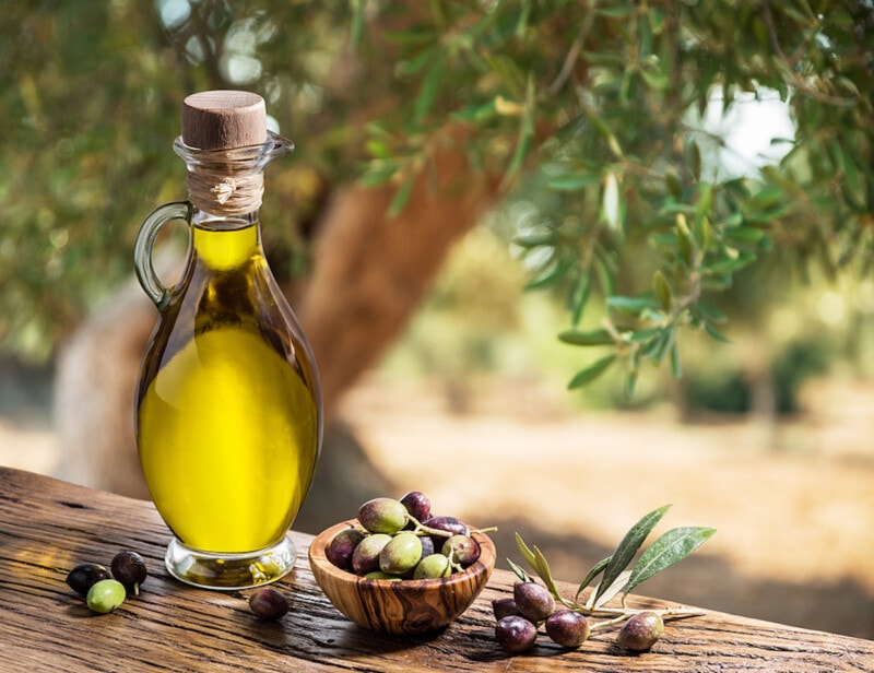 Bottle of olive oil and olive berries are on the wooden table