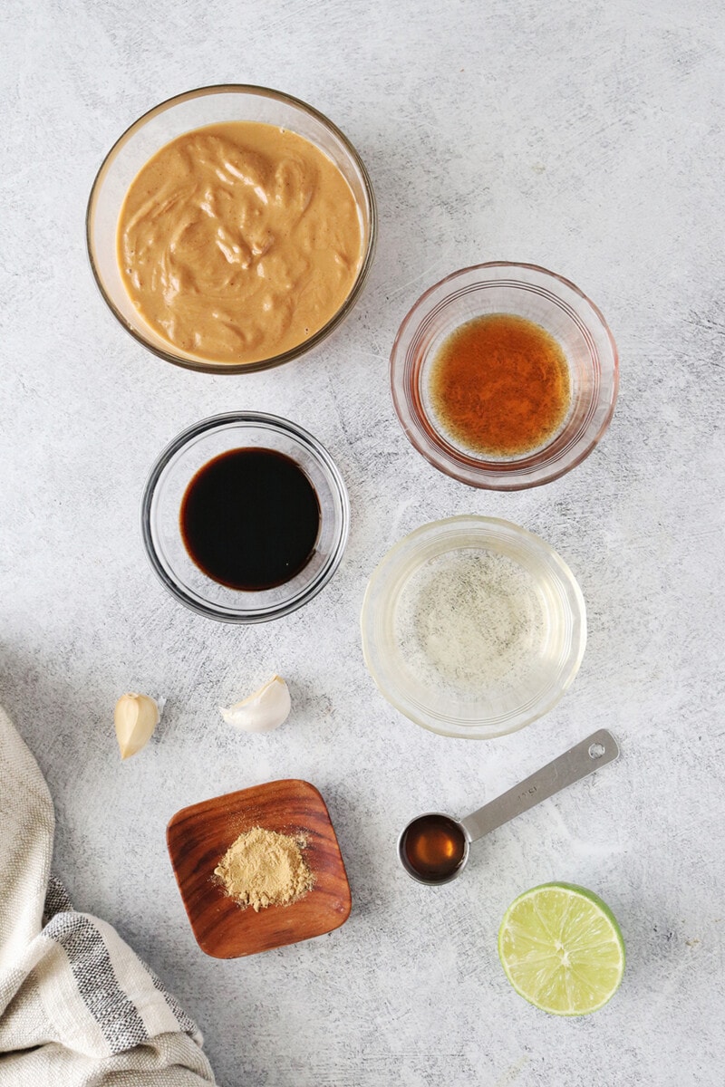 Ingredients for vegan peanut sauce: Peanut butter, rice vinegar, soy sauce, sesame oil, ground ginger, lime juice, maple syrup, and fresh minced garlic.