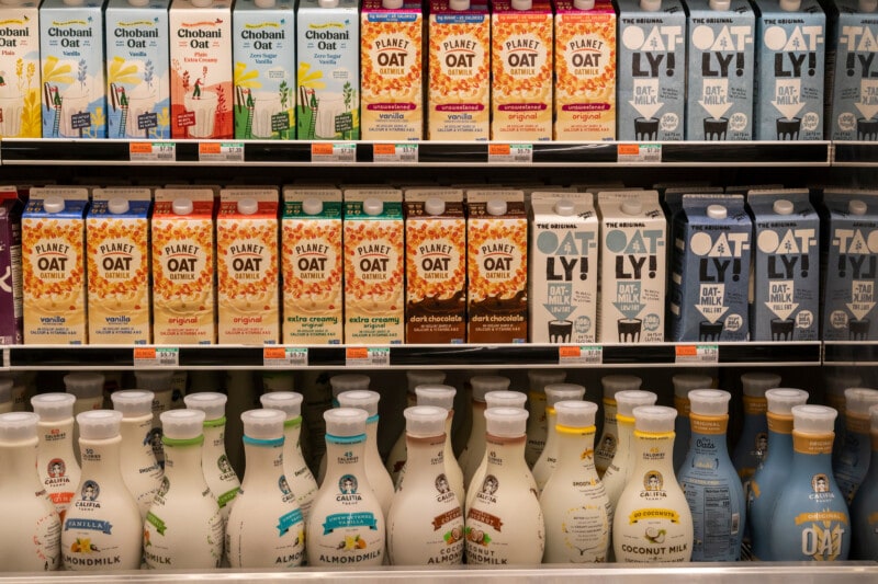 A variety of plant based milk brands in a grocery aisle