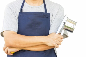 Male chef in blue apron holding a potato ricer