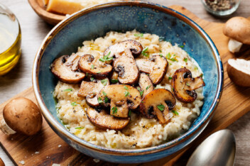 Risotto with brown champignon mushrooms on wooden background.