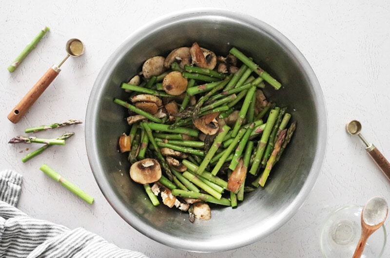 Asparagus stalks and sliced mushrooms in a large bowl