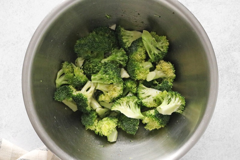 Broccoli tossed with olive oil in a bowl