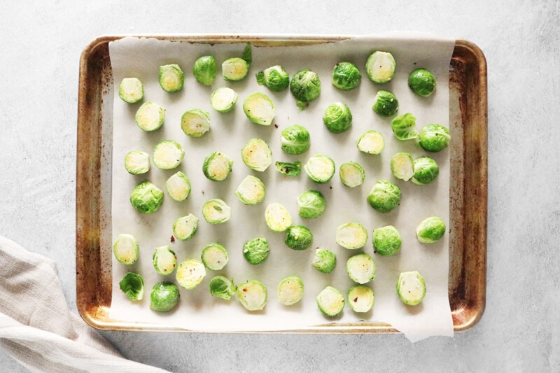 Sliced Brussels sprouts on a metal baking sheet lined with parchment paper