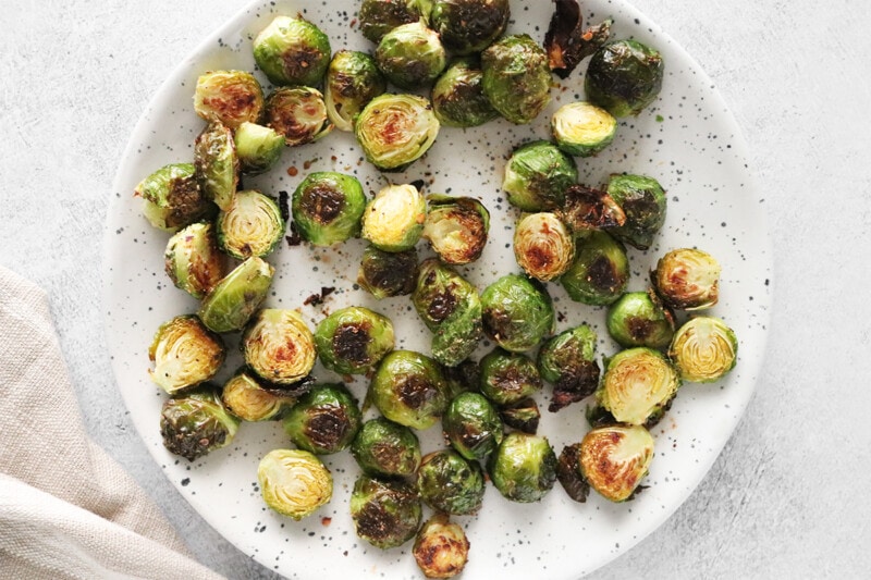 Roasted Brussels sprouts on a white speckled plate on gray background