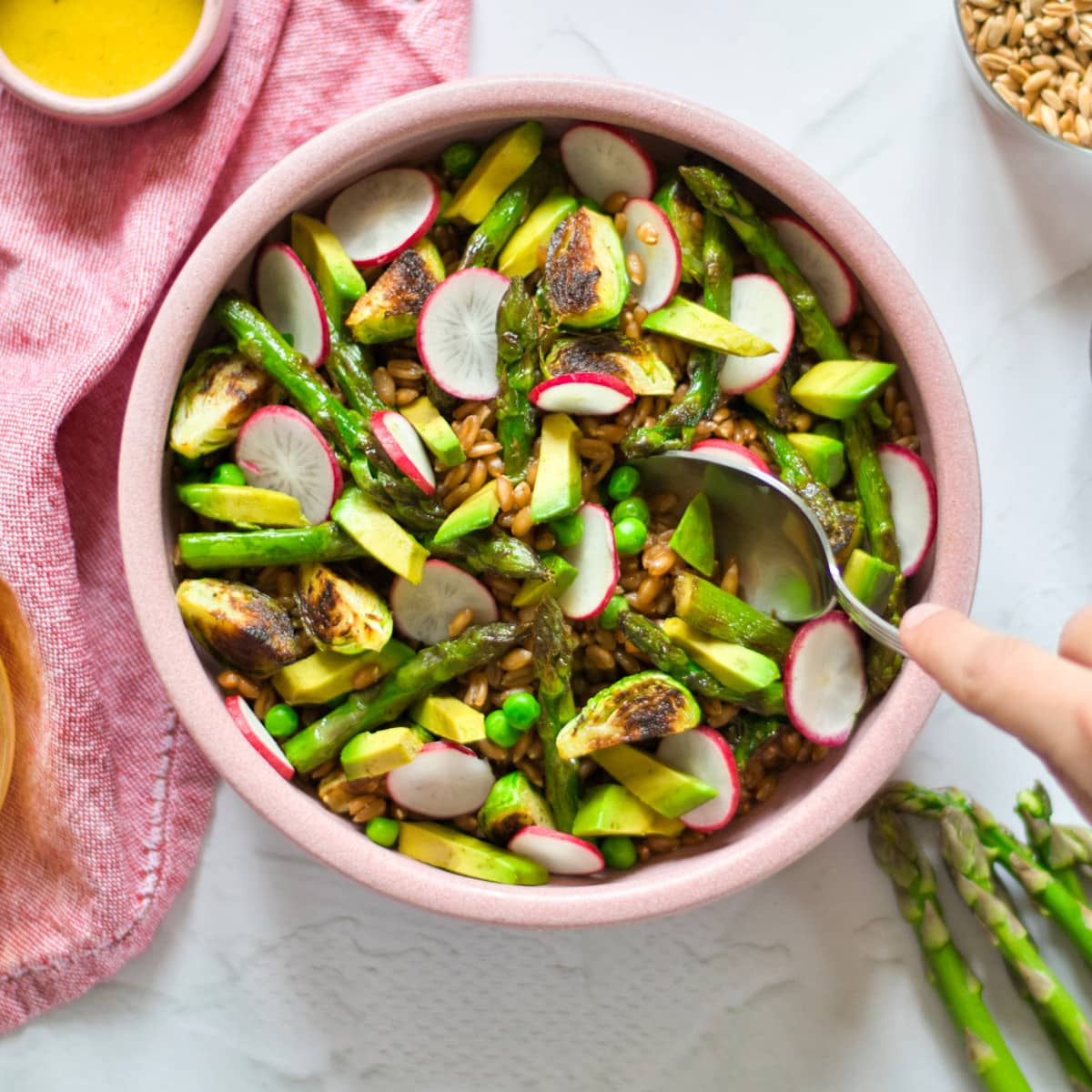 Spring grain salad in a pink bowl.