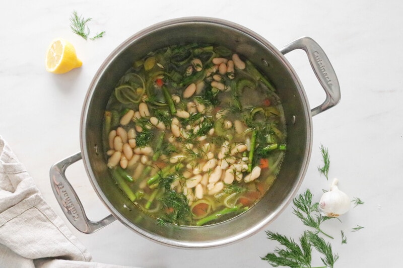 White beans added to spring minestrone soup in a pot.
