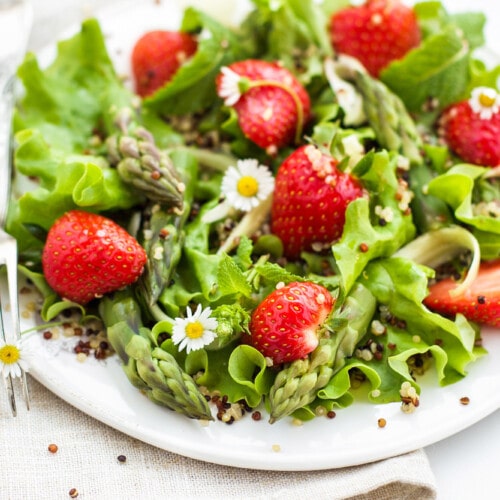 Fresh spring salad topped with strawberry and asparagus.
