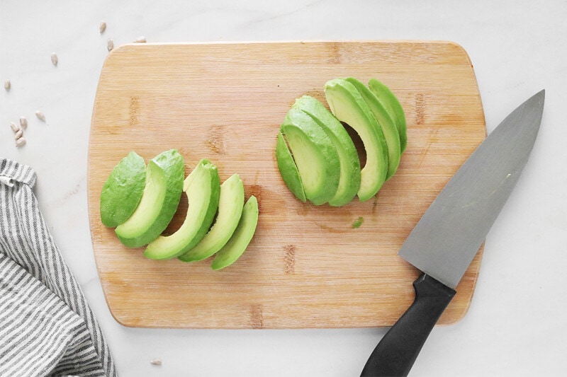Sliced avocado on a wooden cutting board.