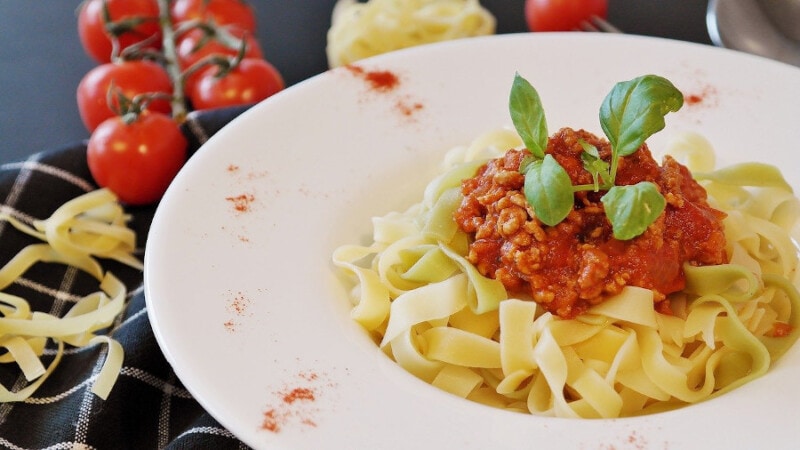 Tagliatelle pasta with bolognese on a white dish.