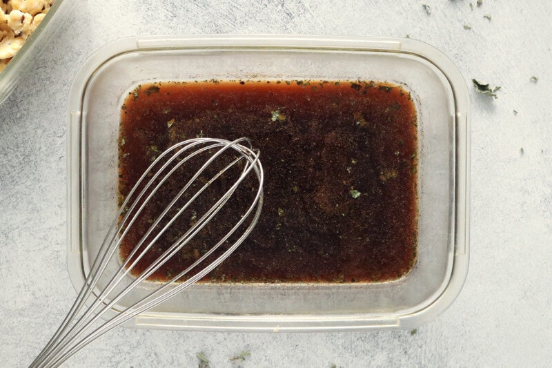 Whisking marinade for tempeh meat crumbles in a glass baking dish