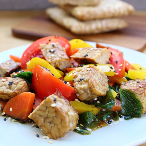 A dish with baked tempeh, peppers, and vegetables.