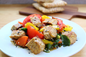 A dish with baked tempeh, peppers, and vegetables.