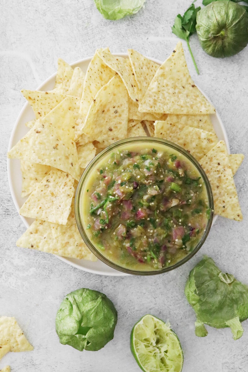 Tomatillo green chili salsa on a plate with tortilla chips.