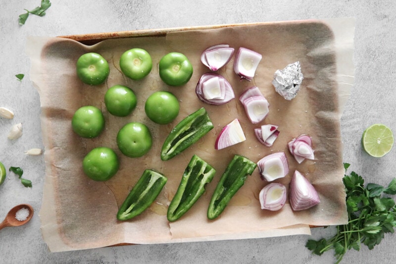 Raw ingredients for tomatillo green chili salsa on a baking sheet.