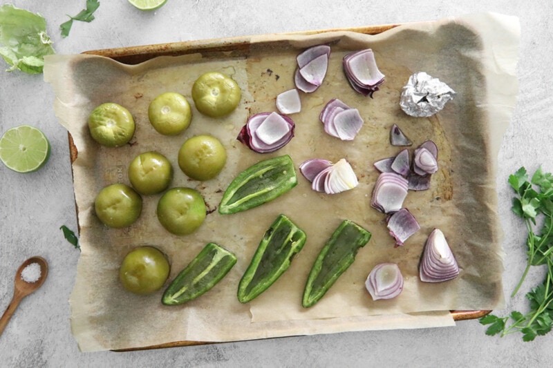 Roasted ingredients for tomatillo green chili salsa on a baking sheet.