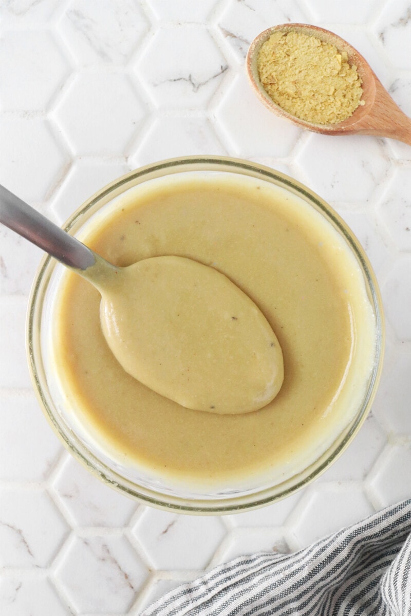 Vegan cheese sauce being spooned out of a glass bowl