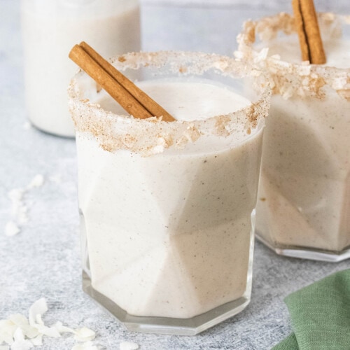 Vegan coquito in a glass with a cinnamon stick